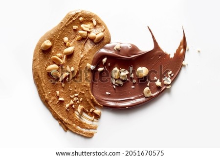 A top view of tasty peanut butter and chocolate paste sprinkled with crushed nuts placed on white table