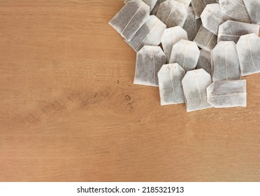 Top View Of A Lot Of Tea Bags In A Pile On A Wooden Background. British, Ceylon Tea. Time To Drink Tea. Antioxidant, Vitamins, Minerals. Hot Drink Treatment For Illness