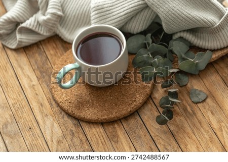 Top view tea mug with eucalyptus and soft knit on wooden table. Cozy morning.