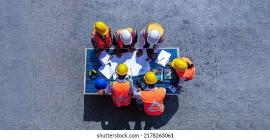 Top view of team of architectural engineer working, meeting, planning with blueprint, Solar photovoltaic equipment, wind turbine business important infrastructure on solar panel at construction site.  - Powered by Shutterstock