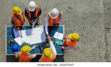 Top view of team of architectural engineer working, meeting, planning with blueprint, Solar photovoltaic equipment, wind turbine business important infrastructure on solar panel at construction site.  - Powered by Shutterstock