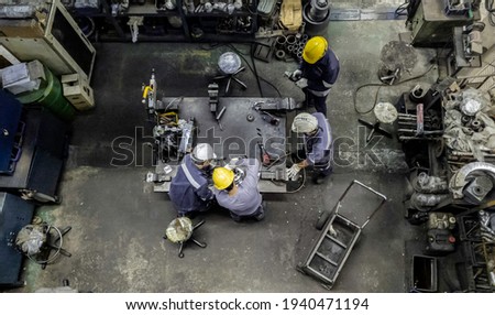Top view of technician and engineer team work to maintain the machinery part in the industry factory, Machanic service team are cutting and grinding part in the workshop