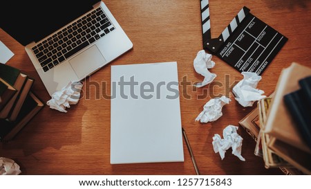 Top View of Text Writer Stuff on Workplace. Closeup of Wooden Desktop with Laptop, Crumpled Paper Sheets, Stacks of Books and Movie Clapper Board. Journalism and Screenwriter Concept