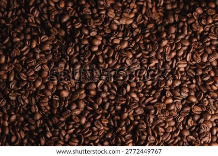 Top view texture Roasted coffee beans filling entire frame on dark background.