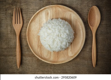 Top View Of Thai Jasmine Rice In Wooden Dish With Napery And Wooden Spoon .