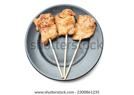 top view a thai pork grill stick or moo ping with bamboo stick  In a black round ceramic dish isolate on a white background.Thai traditional breakfast .horizontal photo