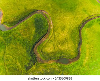 Top view of a thin river and fields around it.