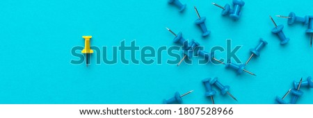Top view of think different concept. Yellow push pin out of the crowd concept over blue backgound.