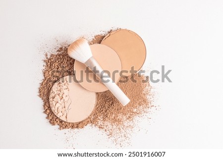 A top view of three blocks of compact powder in different tones and a delicate brush for makeup. white background. Layout for product presentation