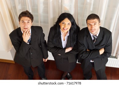 Top view of three business people with different facial expressions(surprised,happy and serious) looking up in an office