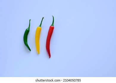 top view of three different colored peppers on a white background