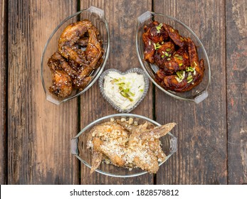 Top View Of Three Flavors Of Chicken Wings - Honey Soy, Buffalo, And Garlic Parmesan Wings, With Ranch Dip At The Center.