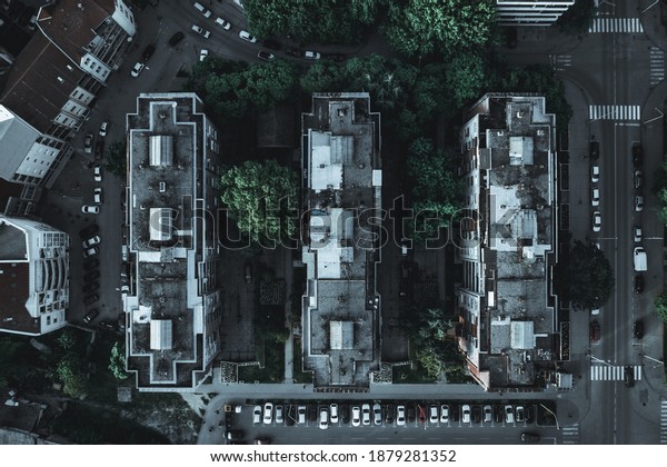 A top view of three identical apartment\
buildings with trees and cars on the\
street