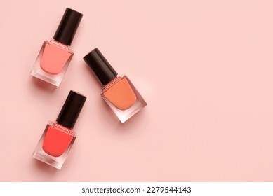 Top view of three matte nail polishes of different colors with copy space for text over pink background. Manicure and pedicure concept