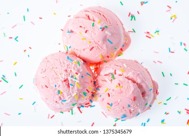 top view of three pink berry scoops of sundae ice cream covered and strewed sprinkles on white background