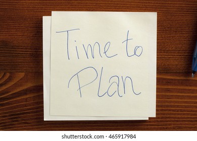 Top view of Time to Plan written note on the wooden desk with pen aside.