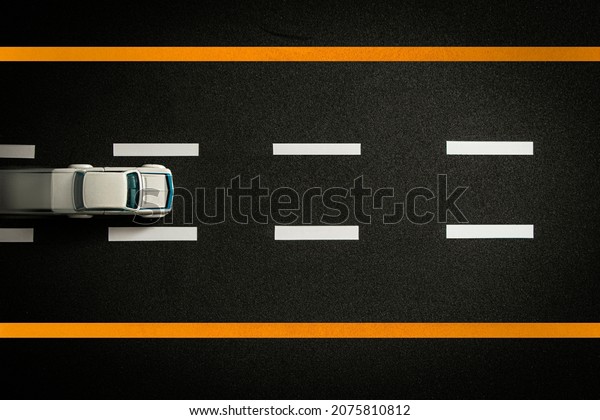 Top\
view of tiny model car speeding on black\
highway.
