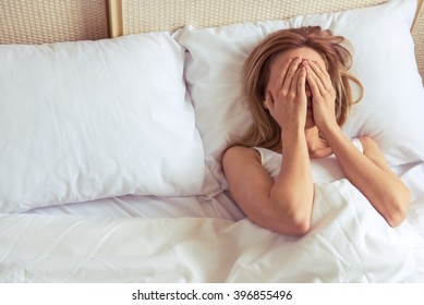 Top View Of Tired Beautiful Girl Covering Her Face While Lying In Bed