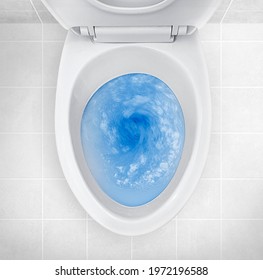 Top view of toilet bowl, blue detergent flushing in it - Shutterstock ID 1972196588