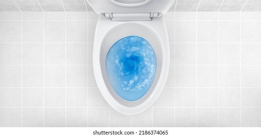 Top view of toilet bowl, blue detergent flushing in it