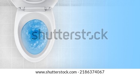 Top view of toilet bowl, blue detergent flushing in it
