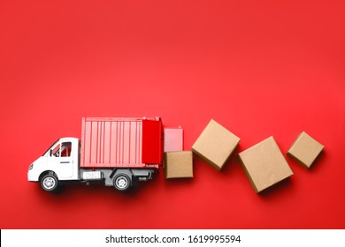 Top view of toy truck with boxes on red background. Logistics and wholesale concept