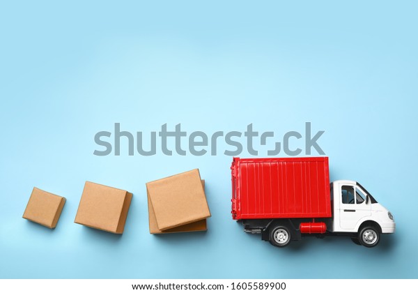 Top view of toy truck with boxes on\
blue background. Logistics and wholesale\
concept