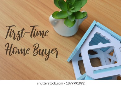 Top view of toy wooden house and plant over wooden background written with text FIRST-TIME HOME BUYER. Business concept. - Shutterstock ID 1879991992
