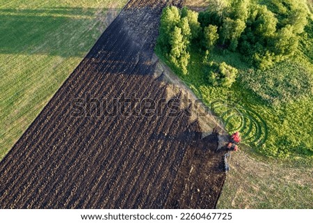 top view of a tractor that plows the land, plowed land and uncultivated