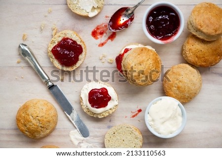 Top view of traditional british scones with clotted cream and strawberry jam for tea time on a wooden table