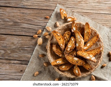 Top view of traditional Italian biscotti Almond Cantuccini in a basket decorated with nuts on wooden table