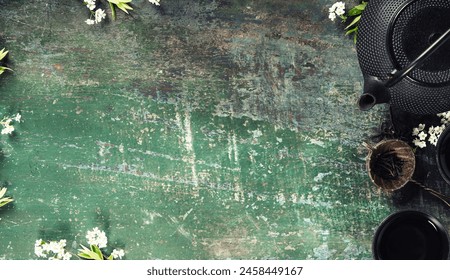 Top view of a traditional tea setup with loose leaves and a black teapot on a weathered wooden surface, evoking a cozy, vintage atmosphere. - Powered by Shutterstock