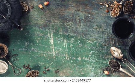 Top view of a traditional tea setup with loose leaves and a black teapot on a weathered wooden surface, evoking a cozy, vintage atmosphere. - Powered by Shutterstock