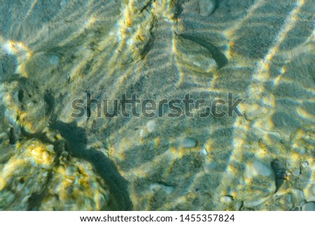 Top view of transparent clear water of river or creek with pebble stones. Abstract nature background