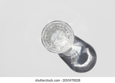 Top View Of Transparent Glass Of Water With Shadow On Light Background.