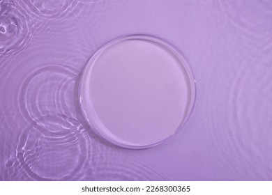 Top view of transparent round empty podium, splashes and bubbles on the purple surface water background. Empty platform for cosmetics. Blank minimal design concept.