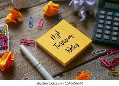 Top view of trash paper, paper clip, calculator, pen and yellow sticky notes written with High Turnover Rates on wooden background.