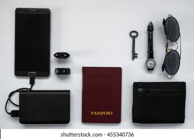 Top View Of Travel Set: Passport, Key, Watches, Sunglasses, Power Bank And Smartphone On White Background 