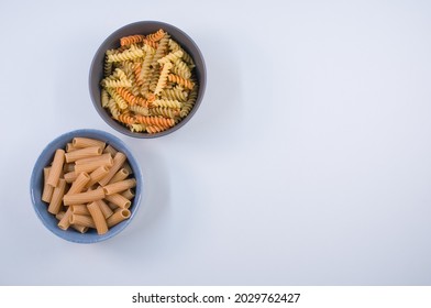 A Top View Of Tri-color Rotini And Rigatoni Pasta On A Bowl Isolated On White Background