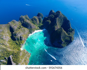Top view of tropical island with limestone rocks, white beach and blue clear water. Aerial view of Maya bay with many boats and speedboats above coral reef. Phi-Phi Islands, Krabi, Thailand.
