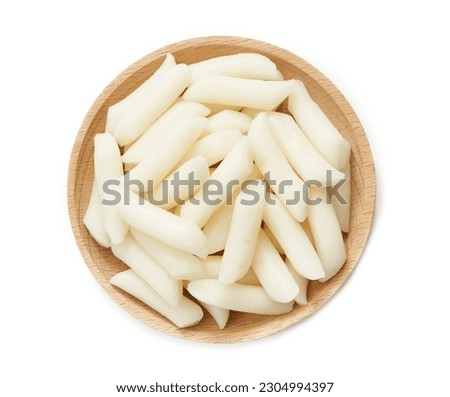 top view Tteok or Korean Rice Cakes in wood plate isolated on white background. pile of Tteok or Korean Rice Cakes in wooden dish isolated. Tteok Korean Rice Cakes flat lay                       