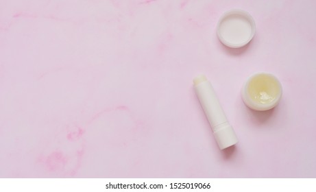 Top View Of A Tube Of White Lip Balm And A Small Round Container Of Solid Perfume.