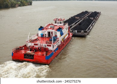 Top view of Tugboat pushing a heavy barge on the river