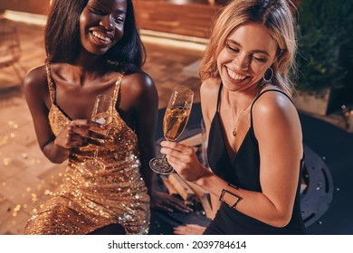 Top View Of Two Beautiful Women In Cocktail Dresses Communicating And Smiling While Spending Time On Luxury Party