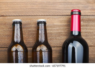 Top View Of Two Beer Bottles And A Wine On Wooden Table.