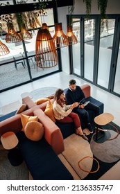 Top view of two businesspeople working in an office lobby. Two modern businesspeople using a digital tablet while having a discussion. Two young entrepreneurs collaborating on a new project. - Shutterstock ID 2136335747