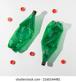 Top View Of Two Empty Plastic Bottles And Red Caps. Consumerism And Environmental Sustainability Concept.