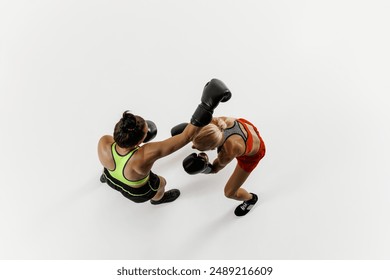 Top view of two female boxers throw powerful punches in intense training session isolated on white background. Focused woman in motion. Concept of combat sport, martial arts, strength, endurance - Powered by Shutterstock