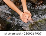 Top view of two hiker hands holding water in their hands to refresh their face in a natural spring of a high mountain stream in the Pyrenees