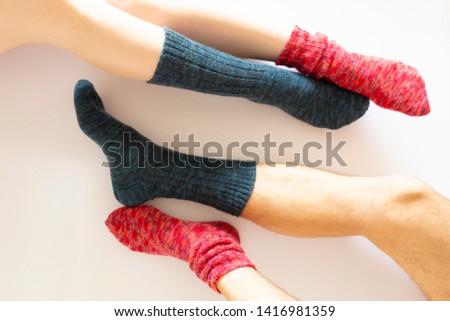 Top view of two pairs of legs wearing a red and a blue sock on white background